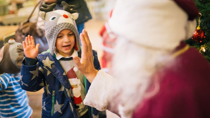 A child greeting Father Christmas with a high five